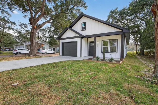 a view of a house with a yard and large tree