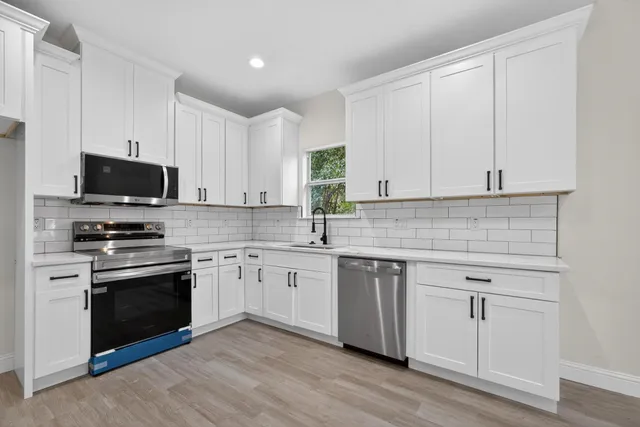 a kitchen with stainless steel appliances granite countertop a sink dishwasher a stove and a microwave oven with cabinets