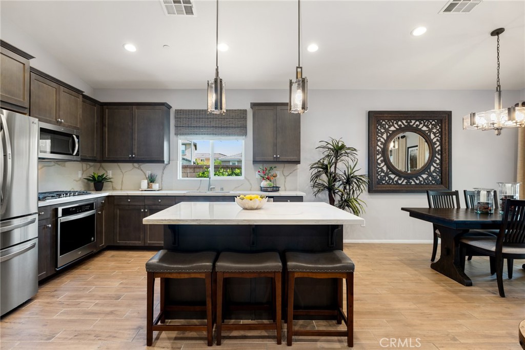 29981 Western Front Drive Menifee, CA 92584 - Photo 21 of 74 a kitchen with kitchen island stainless steel appliances a dining table chairs sink and stove