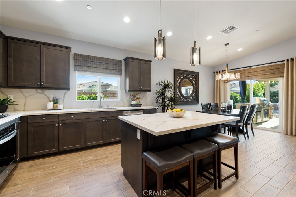 29981 Western Front Drive Menifee, CA 92584 - Photo 22 of 74 a kitchen with a stove a kitchen island a sink cabinets and wooden floor