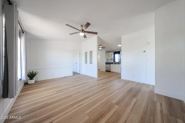 a view of empty room with wooden floor and fan
