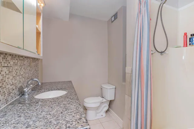 a bathroom with a granite countertop toilet and a sink