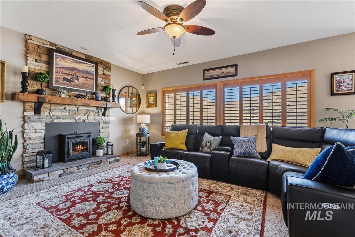11660 Timber Butte Road Sweet, ID 83670 - Photo 8 of 49 Stone-clad fireplace with a wood mantel, ceiling fan with integrated lighting, and plantation shutters