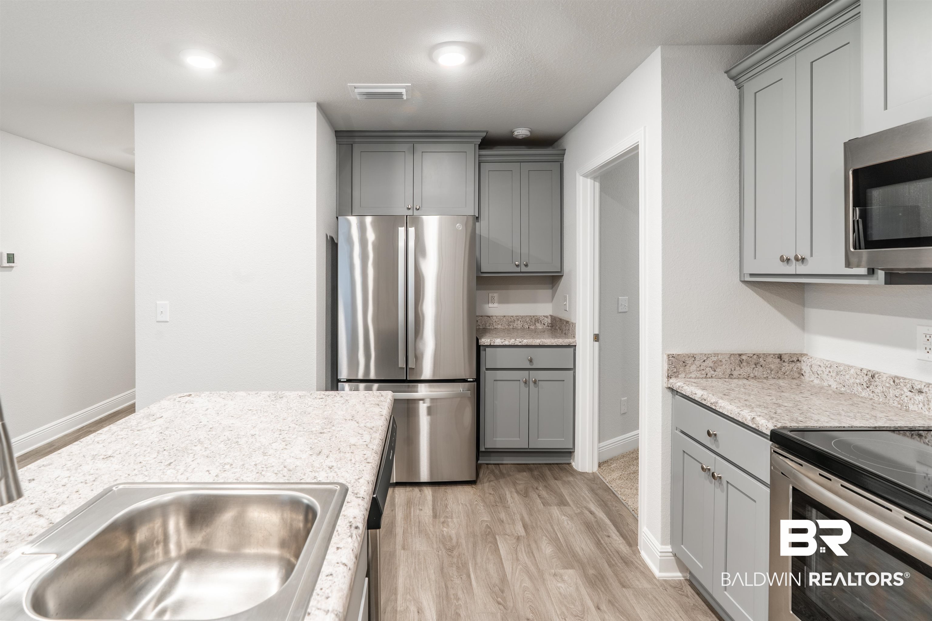 1906 Stonepine Drive South Semmes, AL 36575 - Photo 9 of 30 Kitchen featuring gray cabinets, stainless steel appliances, light wood-style flooring, and light stone countertops
