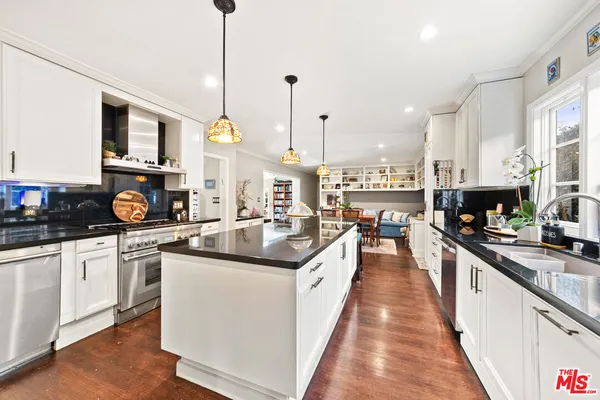 a kitchen with stainless steel appliances kitchen island granite countertop a stove a sink a refrigerator and chairs