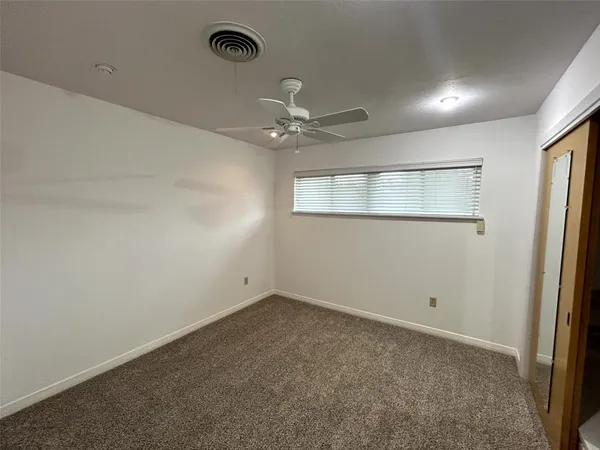 an empty room with a chandelier fan and windows