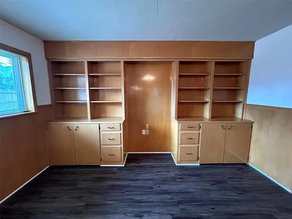 a view of an empty room with wooden floor and windows