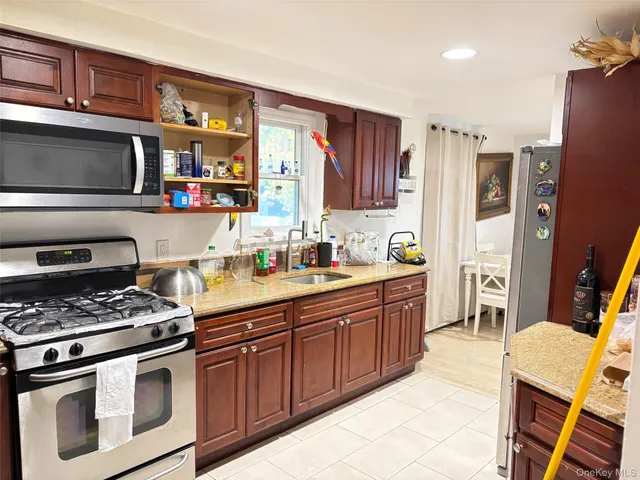 a kitchen with stainless steel appliances granite countertop a stove top oven a sink dishwasher and a refrigerator with wooden cabinets