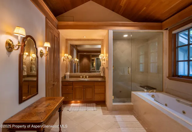 a bathroom with a tub a sink and mirrors