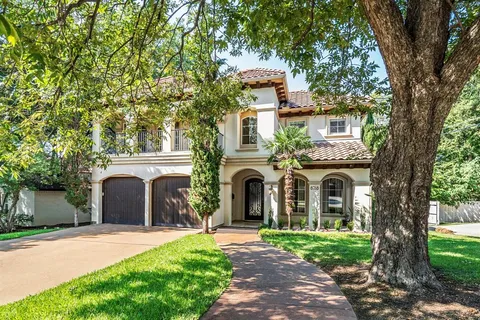 a front view of a house with a garden and a tree