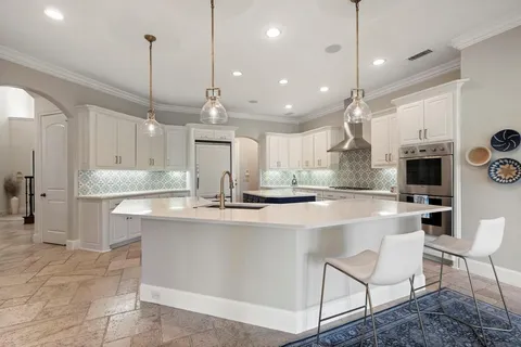 a large kitchen with kitchen island a flat screen tv and a refrigerator
