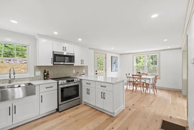 a kitchen with white cabinets and wooden floor