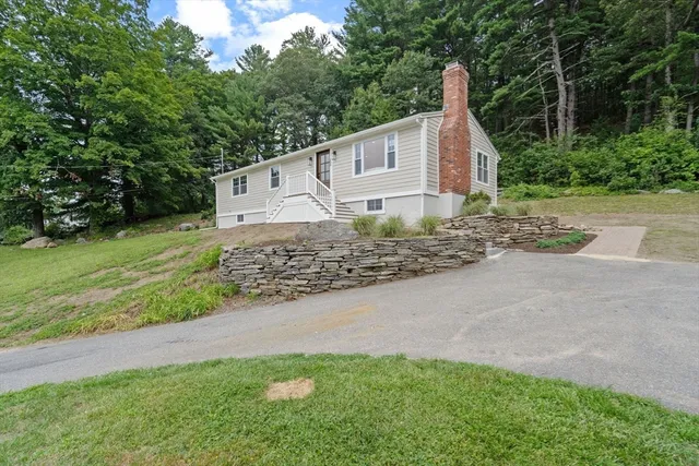 a view of a house with a yard and large tree