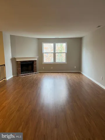 an empty room with wooden floor fireplace and windows