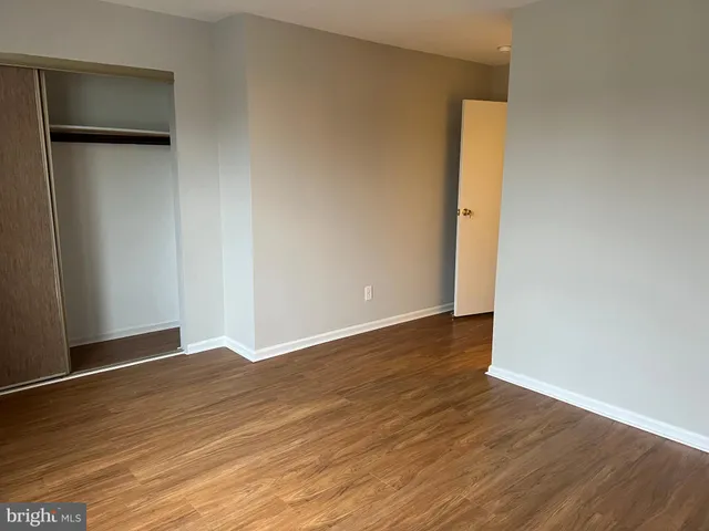 a view of an empty room with wooden floor and closet