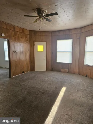 an empty room with windows and fan