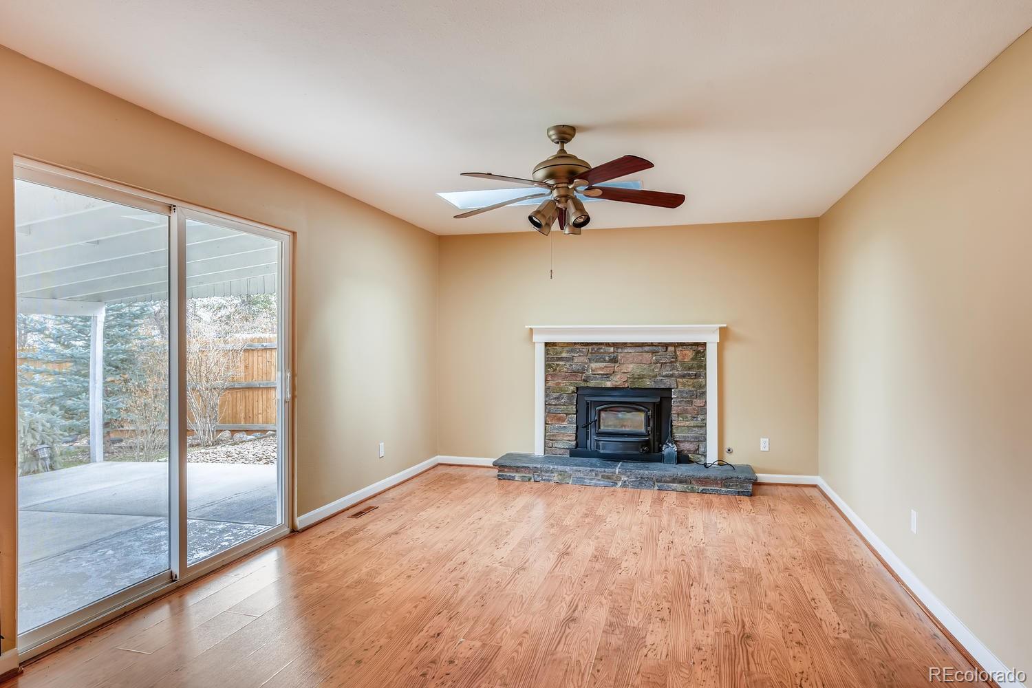 6734 Kendall Street Arvada, CO 80003 - Photo 14 of 36 wooden floor fireplace and windows in an empty room