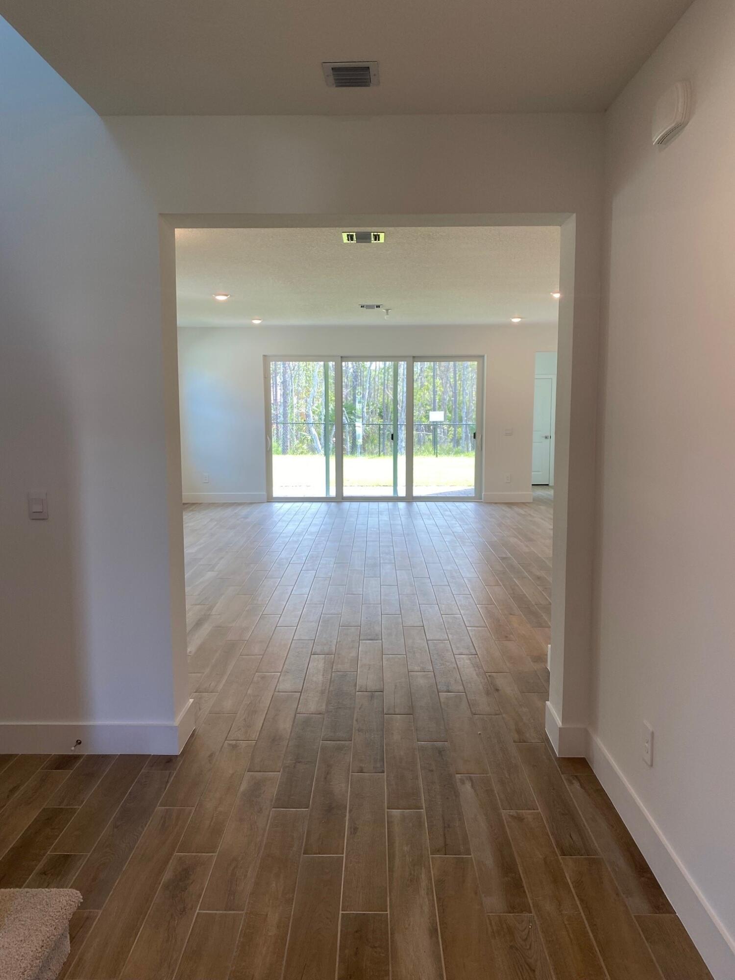 6830 Southeast Park Trace Drive Stuart, FL 34997 - Photo 2 of 20 wooden floor in an empty room with a window