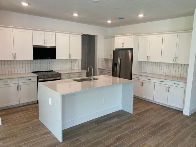 a kitchen with kitchen island white cabinets and stainless steel appliances