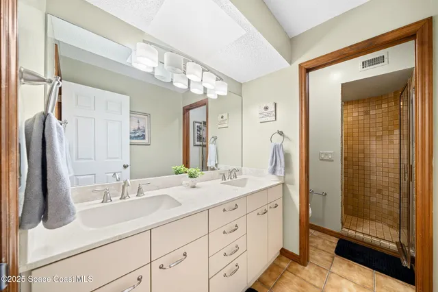 a bathroom with a double vanity sink mirror and shower