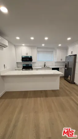 a large white kitchen with kitchen island a sink a stove a refrigerator and a stove