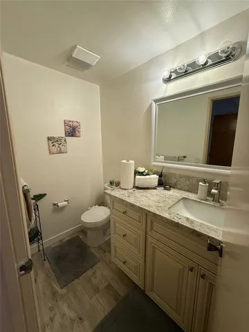 a bathroom with a granite countertop sink mirror and toilet