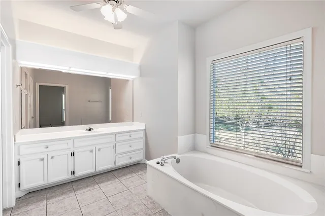 a spacious bathroom with a tub sink and mirror