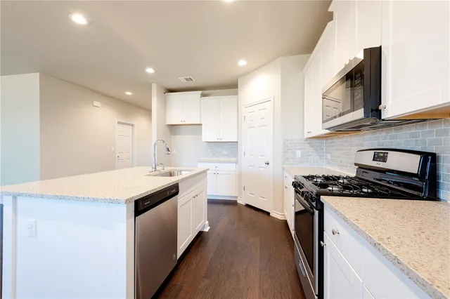 a kitchen with a sink stove top oven and cabinets
