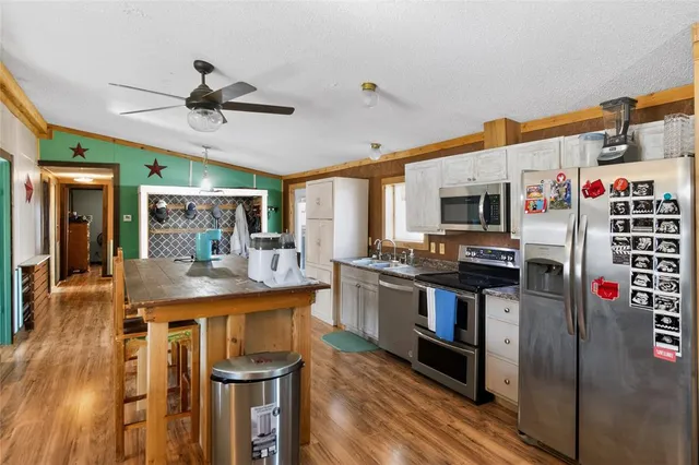 a kitchen with stainless steel appliances kitchen island granite countertop a table chairs in it and a window