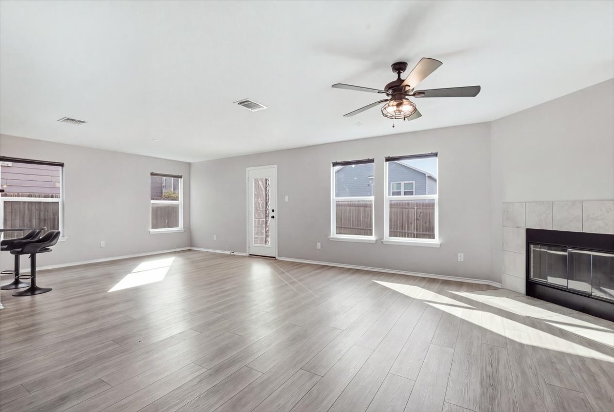 104 Rooster Way Jarrell, TX 76537 - Photo 8 of 33 Natural light streams across a spacious room anchored by a tiled fireplace and wood-inspired flooring.