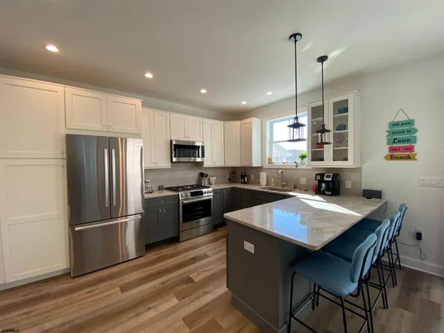 a kitchen with granite countertop a refrigerator a stove a sink a dining table and chairs with wooden floor