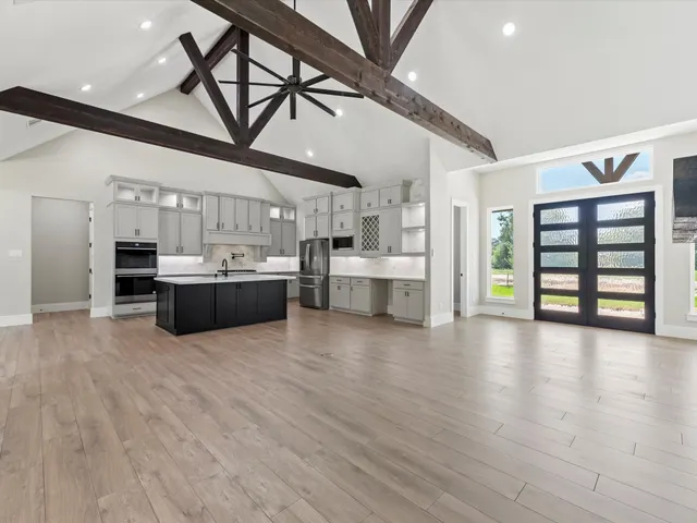 a large kitchen with stainless steel appliances granite countertop a lot of cabinets and wooden floors