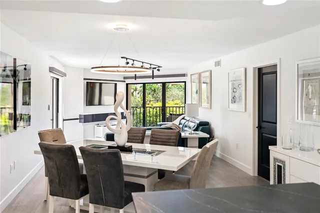 a kitchen with stainless steel appliances kitchen island granite countertop a table chairs in it and a window