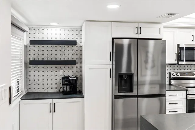 a kitchen with stainless steel appliances granite countertop a sink a stove and a refrigerator