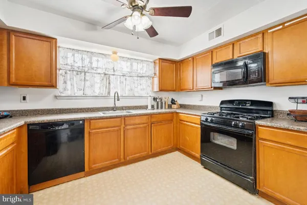 a kitchen with stainless steel appliances granite countertop a sink a stove top oven a chimney cabinets and a window