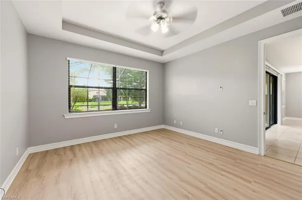 an empty room with windows and fan