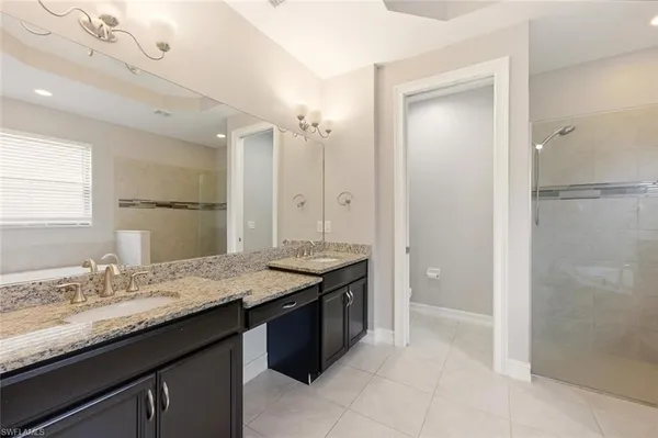 a bathroom with a granite countertop tub sink shower and mirror