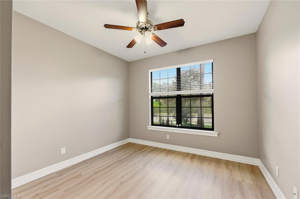 14513 Tuscany Pointe Trail Naples, FL 34120 - Photo 19 of 31 an empty room with wooden floor chandelier and windows