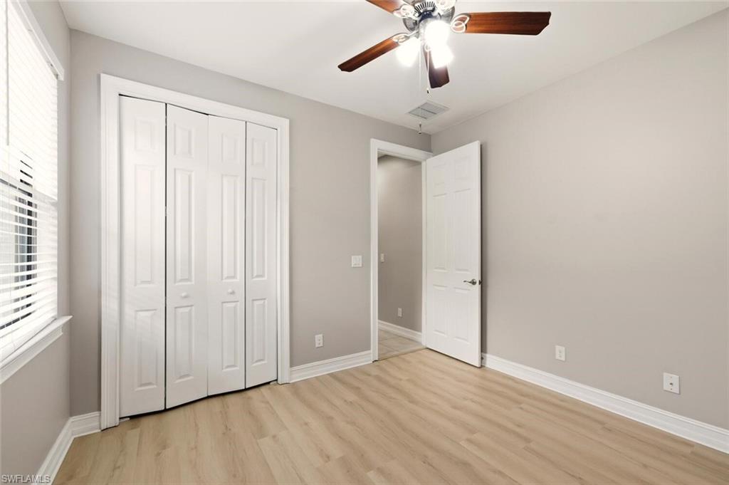 14513 Tuscany Pointe Trail Naples, FL 34120 - Photo 23 of 31 an empty room with wooden floor chandelier fan and windows