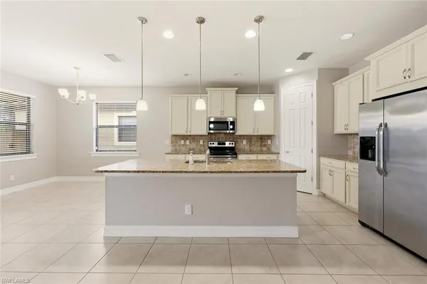 a view of a electric appliances in kitchen and empty room with windows