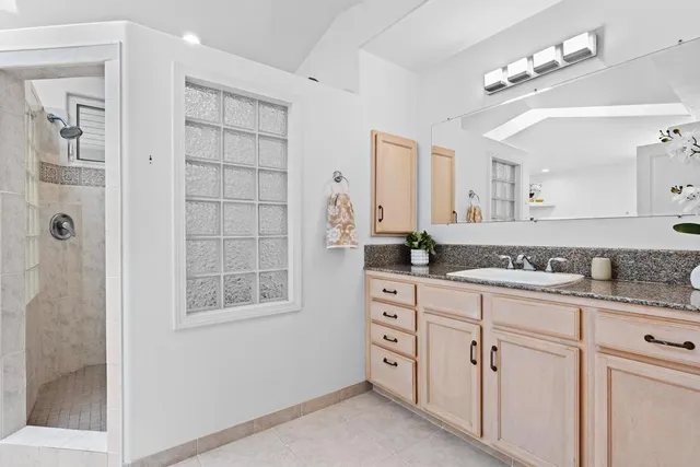 a spacious bathroom with a granite countertop sink a mirror and a shower