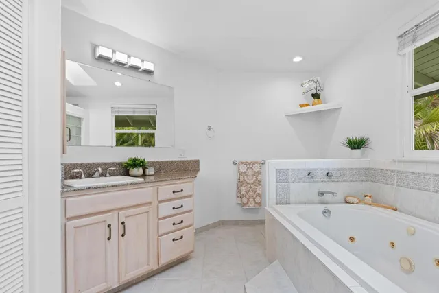a bathroom with a bathtub a sink a vanity and a window