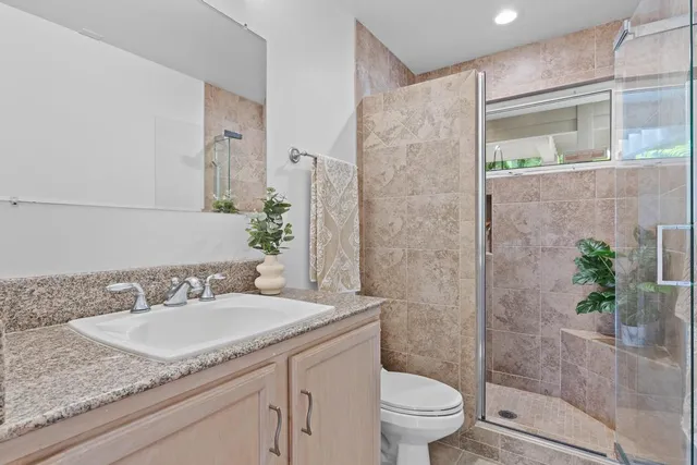 a bathroom with a granite countertop sink a toilet and shower