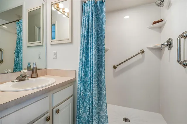 a bathroom with a granite countertop bathtub shower sink vanity and toilet