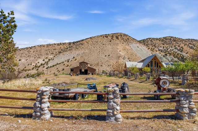 811 East Canyon Road Mayfield, UT 84643 - Photo 47 of 57 Rural property featuring a wood-sided main residence with a prominent A-frame window design, a separate barn structure, and a fenced perimeter with stone pillars