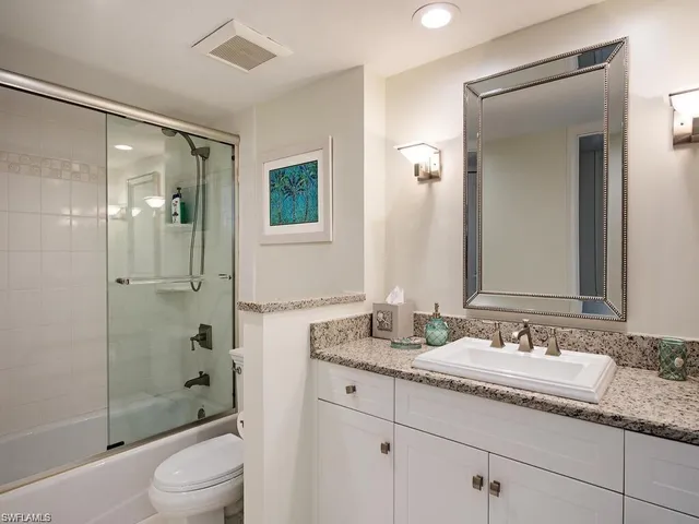a bathroom with a granite countertop sink a toilet and shower