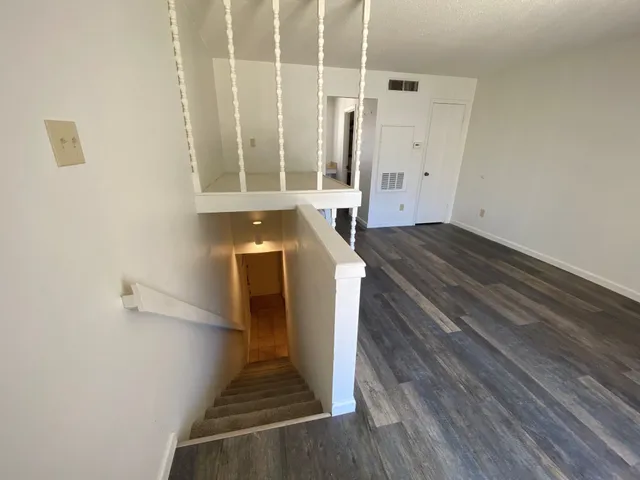 a view of a hallway with wooden floor and staircase
