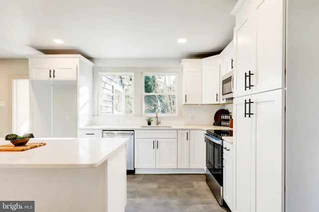 a kitchen with a sink a stove a refrigerator and white cabinets