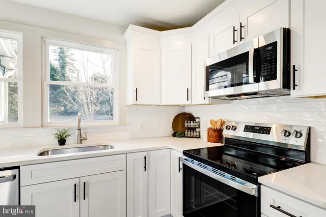 a kitchen with stainless steel appliances a stove a sink a microwave cabinets and a window