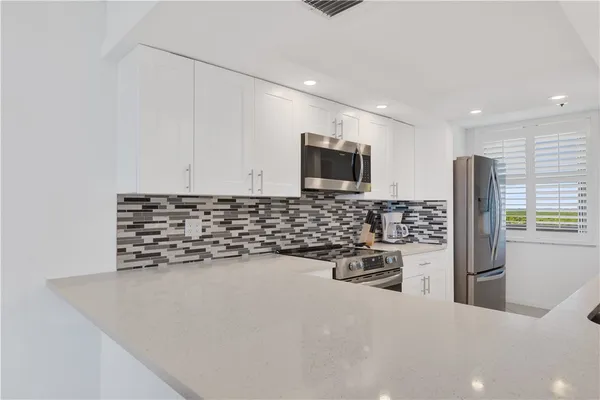 a kitchen with granite countertop a sink stainless steel appliances and white cabinets